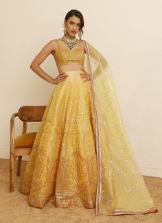 Introducing the sunset-inspired Yellow Embroidered Lehenga Set, crafted from luxurious organza. The yellow lehenga features a stunning blend of yellow shades and vibrant orange embroidery, enhanced with exquisite foil work. Teamed with a bralette-style blouse, meticulously adorned with nalki and sequin embroidery, this ensemble adds a touch of contemporary glamour. Completed with a delicate organza dupatta, featuring shimmering sequin embroidery and a refined gold border. Perfect for special occasions like Sangeet, Mehendi, Haldi, or as a wedding guest outfit. Composition : Lehenga, Blouse & Dupatta : Organza Care: Dry Clean Only and Vacuum Storage This product can be customized for sleeves, length and colour Delivery : 4-6 weeks as the product is hand crafted. Check Size Guide or choose M Studio Iris, Lehenga Pattern, Orange Embroidery, Organza Lehenga, Yellow Lehenga, Draping Fashion, Vacuum Storage, Embroidered Lehenga, Indian Wedding Wear