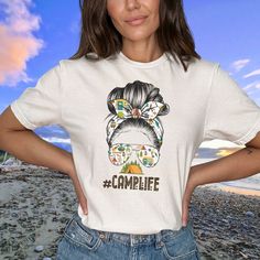 Looking for a great gift for that Camping Mom in your life? This is it. The #Camplife T-shirt! This shirt captures the spirit of adventure and embraces the untamed wilderness. With an image of a mom rocking a messy bun, it's a playful nod to all the fearless moms out there who know how to conquer the great outdoors. Whether you're pitching tents, roasting marshmallows, or swapping stories by the campfire, this T-shirt is a badge of honor for those who appreciate the simple joys of nature. So gather your gear, embrace the wild, and proudly wear your #Camplife T-shirt as you embark on unforgettable adventures under the open sky! Adventure Shirts, Camping Tee, Hiking Tshirt, Adventure Gifts, Roasting Marshmallows, Camp Life, Simple Joys, Open Sky, Adventure Shirt