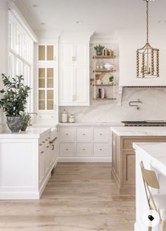 a large kitchen with white cabinets and wood flooring is seen in this image from the front view