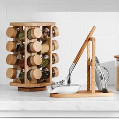 a wooden spice rack with spices and spoons on a white countertop next to an open jar