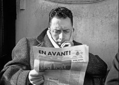 a man reading a newspaper while holding his head in his hands and covering his mouth