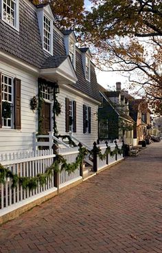 a street lined with white houses covered in christmas wreaths