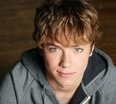 a young man wearing a gray hoodie looking at the camera