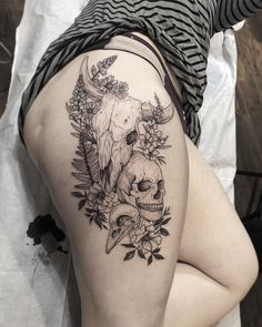 a woman's thigh with flowers and skulls on it