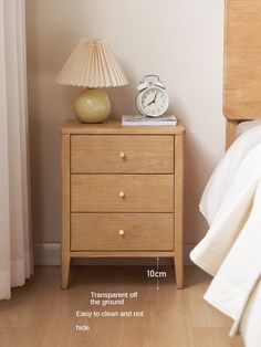 a nightstand with an alarm clock on it next to a bed