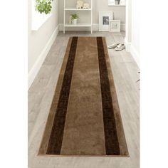 a brown and tan area rug in a white room with bookshelf behind it