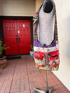 a dress hanging on a stand in front of a red door and brick flooring