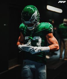 a football player wearing a green uniform and white gloves with his hands in his pockets