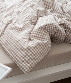 an unmade bed with a brown and white checkered comforter on top of it