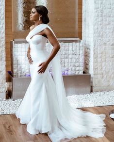 a woman in a white wedding dress standing on a wooden floor