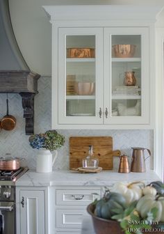 a kitchen with white cabinets and silverware on the counter top, along with a wooden cutting board