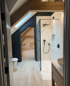 an attic bathroom with white tile and wood flooring is seen through the open doorway