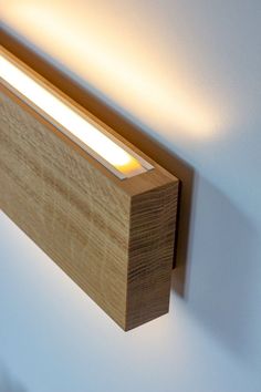 a light that is on the side of a wooden wall mounted fixture with a white light