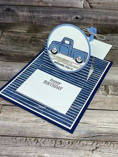 a blue and white greeting card with a truck on it, sitting on top of a wooden