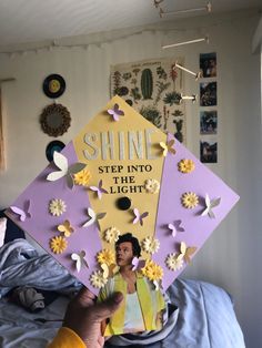 a person holding up a sign that says shine step into the light with flowers on it