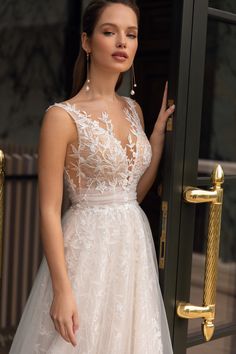 a woman in a wedding dress is standing by a door and pointing at the camera