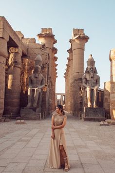 two women standing in front of statues at the egyptian museum, one wearing a beige dress