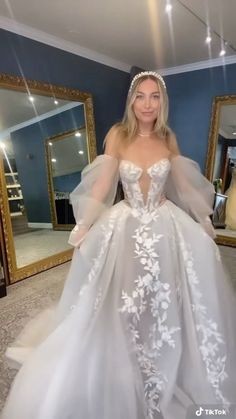 a woman in a wedding dress standing in front of a mirror with her hands on her hips