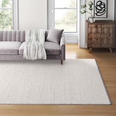 a living room with a gray couch and white rug