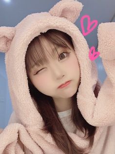 a girl in a pink bear costume posing for the camera with her hands on her head