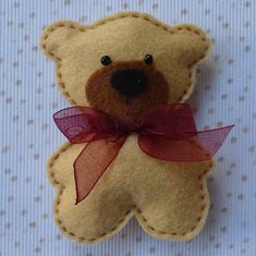 a brown teddy bear with a red bow on it's head sitting on a polka dot surface