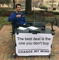 a man sitting at a table with a sign that says, the best deal is the one you don't buy change my mind