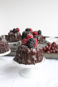 chocolate bundt cake with raspberries and blackberries on top, sitting in front of other desserts