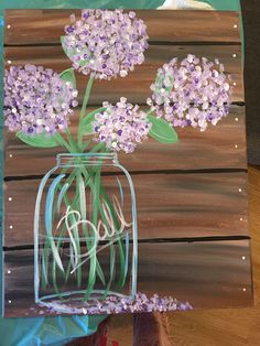 a painting of purple flowers in a mason jar with the word love painted on it