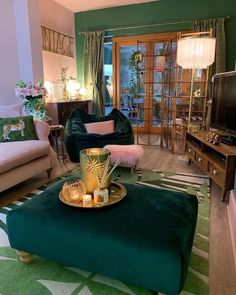 a living room filled with furniture and a flat screen tv sitting on top of a green ottoman