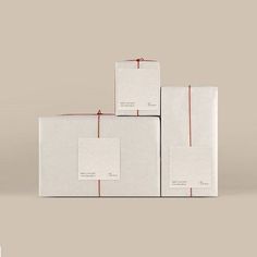 three boxes wrapped in white paper with red ribbon