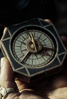 a person holding a small compass in their hand and looking at it with both hands