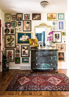 a room filled with lots of framed pictures on the wall and a dresser in front of it