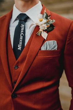 a man in a red suit with a black tie and flower boutonniere