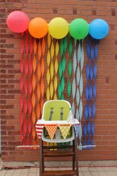 a baby's high chair in front of a wall decorated with balloons and streamers