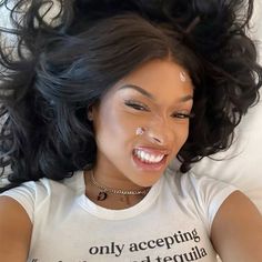 a woman laying on top of a bed wearing a t - shirt that says only accepting