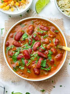 a bowl of chili with beans and cilantro in it next to other bowls