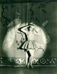 an old black and white photo of a woman in a dress with a bird on her head