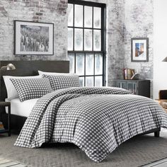 black and white checkered comforter set in a bedroom with brick wall behind it