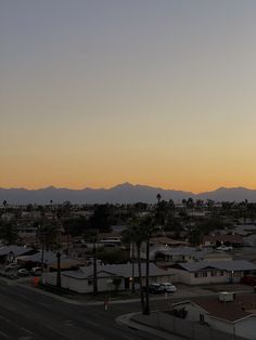 an airplane is flying over a city at sunset or sunrise with palm trees and mountains in the background