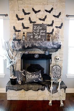 a fireplace decorated for halloween with black and white decorations on top, bats hanging from the mantel