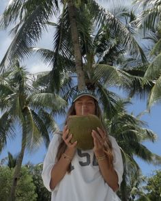 a woman holding a coconut in front of her face