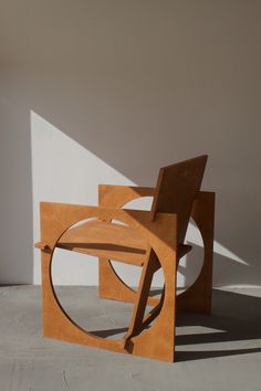 a wooden chair sitting on top of a cement floor next to a white wall and window