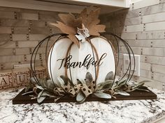 a white pumpkin sitting on top of a counter next to a sign that says happy thanksgiving