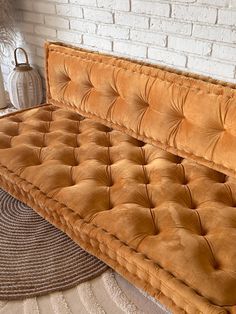 a brown couch sitting on top of a rug next to a white brick wall