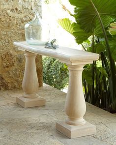 a white bench sitting on top of a stone floor next to a potted plant