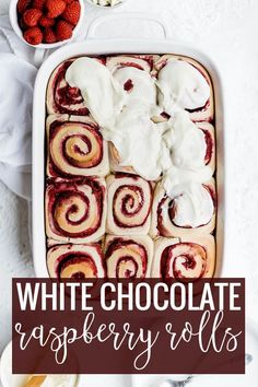 white chocolate raspberry rolls in a baking dish with whipped cream on top and strawberries next to it