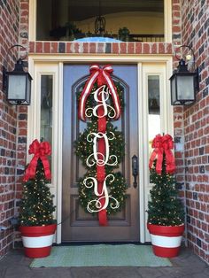 two christmas wreaths with red bows and monogrammed letters are on the front door