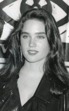 black and white photograph of a woman in leather jacket with large earrings on her head