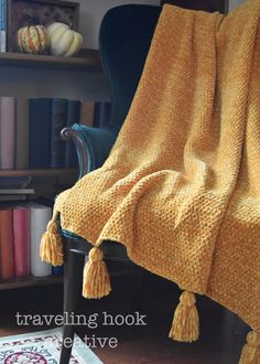 a yellow blanket sitting on top of a chair in front of a book shelf filled with books