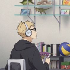 a man sitting in front of a computer with headphones on while holding a book